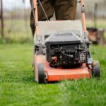 Mowing grass with an orange lawn mower.